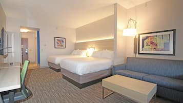 A hotel room with a bed, a sofa, a desk, and a chair.