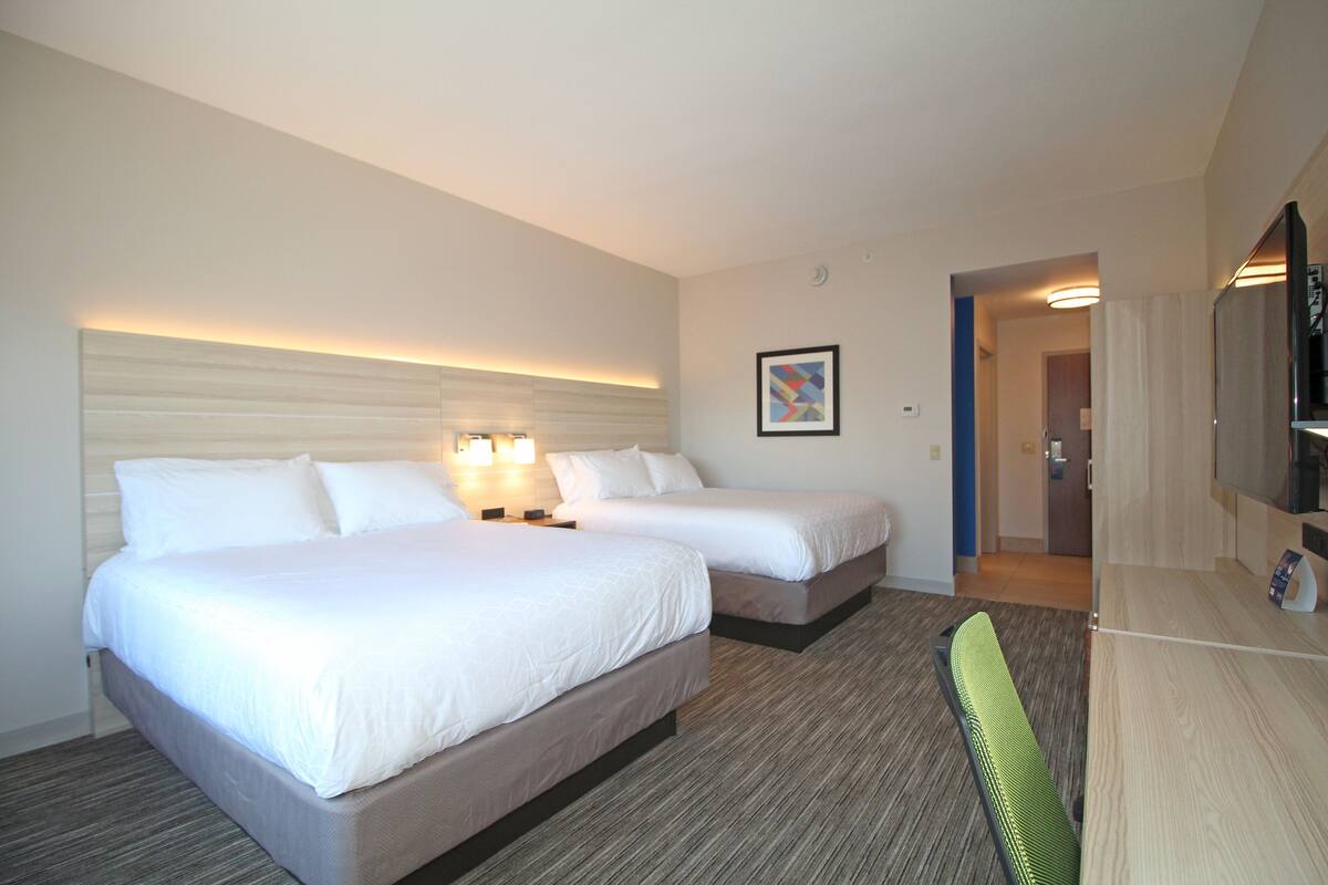 Une chambre d’hôtel avec deux lits, un bureau, une chaise et un téléviseur.