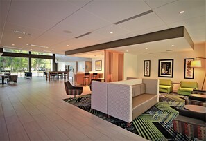 A modern hotel lobby with a reception desk, seating area, and large windows. - Holiday Inn Express & Suites Ocala by IHG (Ocala)