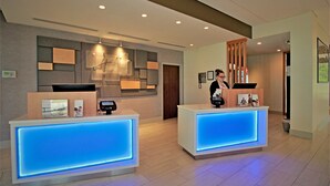 Zona de recepción de hotel con dos mostradores, diseño interior moderno y una recepcionista.