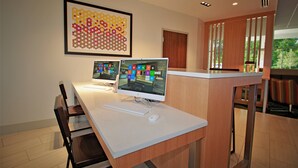 Un espacio de oficina moderno con dos computadoras de escritorio, una obra de arte abstracta enmarcada y un mostrador de recepción de madera.