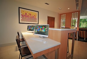 A modern office space with two desktop computers, a framed abstract art piece, and a wooden reception desk.