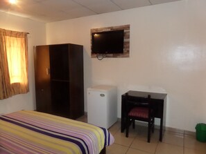 A room with a bed, a desk, a television, and a wardrobe. - Ivory Suites (Abuja)
