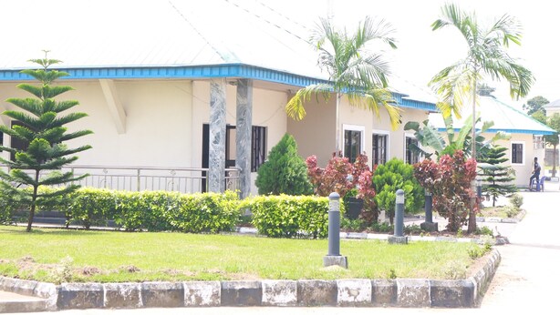 A building with a blue roof and a garden with various plants and a pathway. - L & L Executive Hotels and Suites (Uyo)