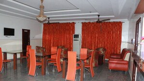 A dining area with a table and chairs, a ceiling fan, and red curtains. - L & L Executive Hotels and Suites (Uyo)