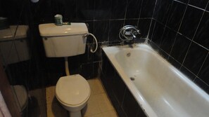 A small bathroom with a toilet and a bathtub. - Labod Hotel (Ibadan)