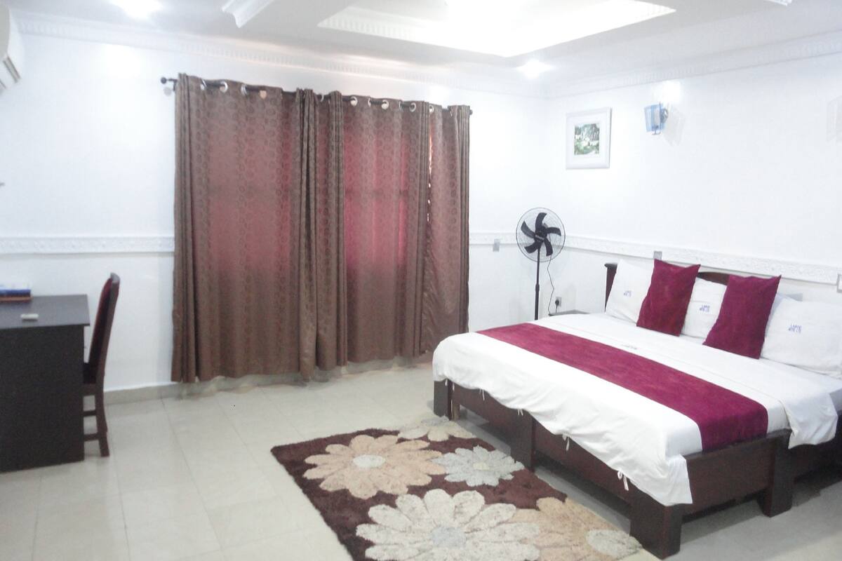 A bedroom with a bed, a desk, and a chair.