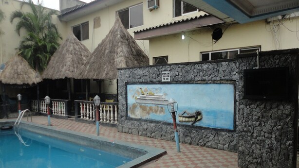 A swimming pool with a checkered floor, a mural of a boat, and thatched umbrellas. - Labod Hotel (Ibadan)