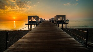 Une jetée en bois menant à des chaises de plage, avec un coucher de soleil en arrière-plan.