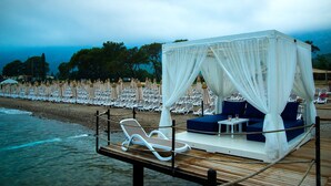 Un cabanon de plage avec un auvent, des chaises longues et une petite table.