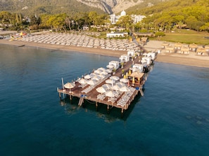 An aerial view of a coastal resort with a pier extending into the water, featuring sun loungers and umbrellas. -  Juju Premier Palace - Ultra All Inclusive (Kemer)