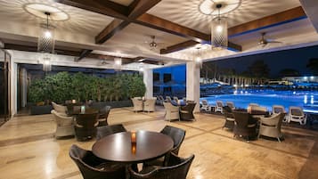 A poolside area with wicker furniture, ceiling fans, and a view of the pool.