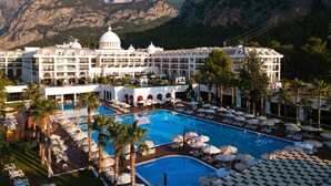 Un complexe hôtelier doté d’une grande piscine, de nombreux balcons et offrant une vue sur un paysage montagneux.