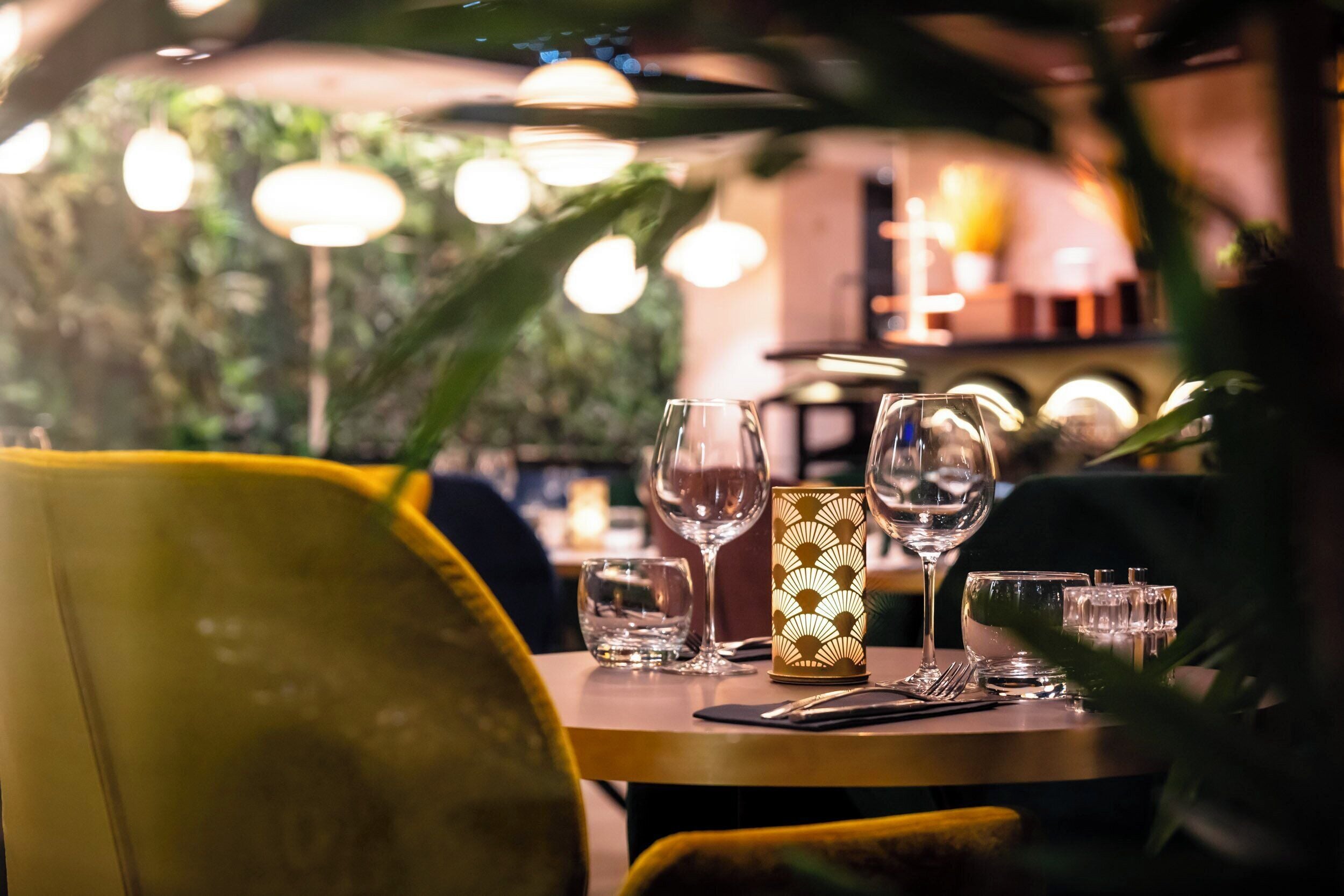 A restaurant table set with wine glasses, a candle, and cutlery.