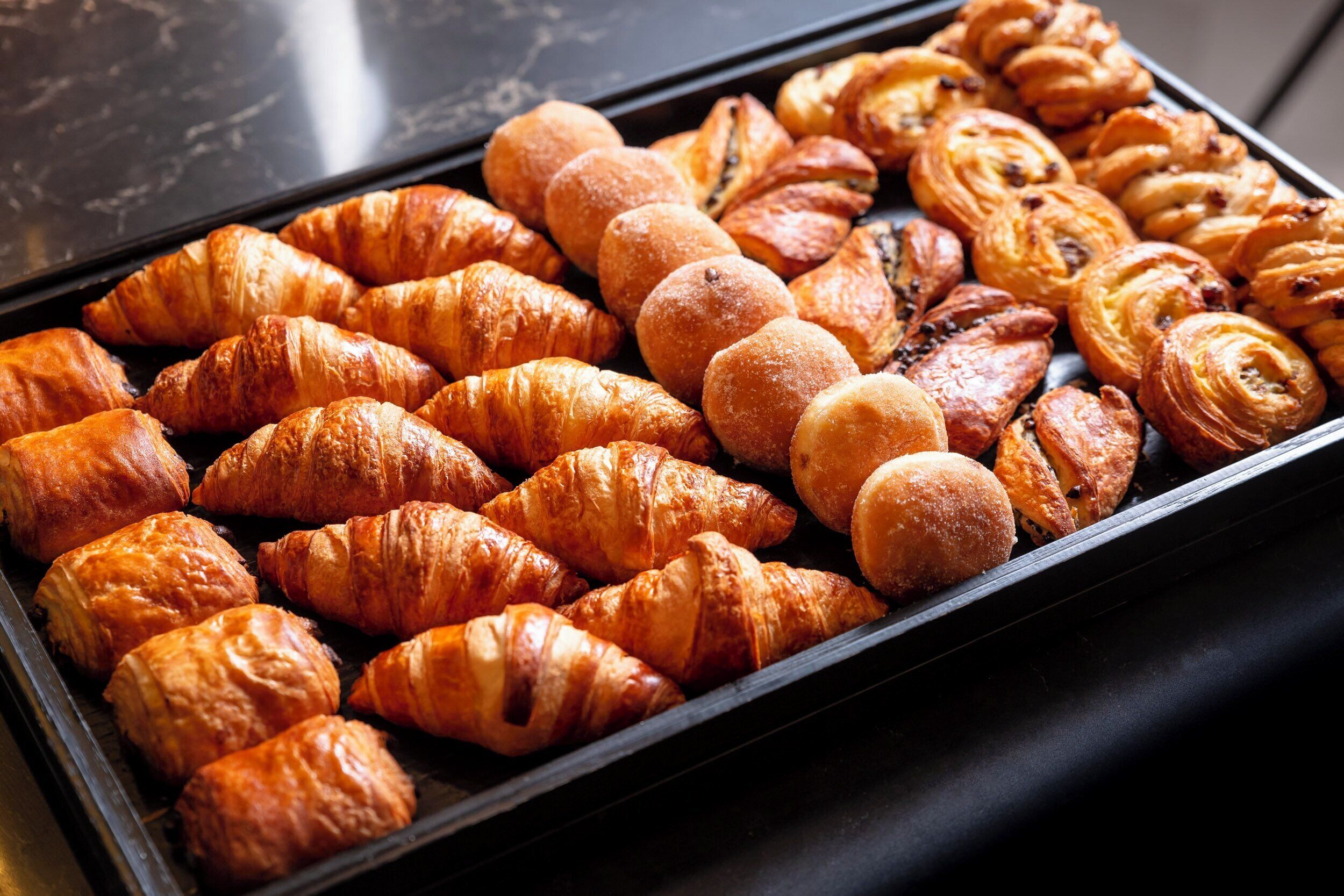 Eine Auswahl an gebackenen Köstlichkeiten, darunter Croissants und Gebäck.