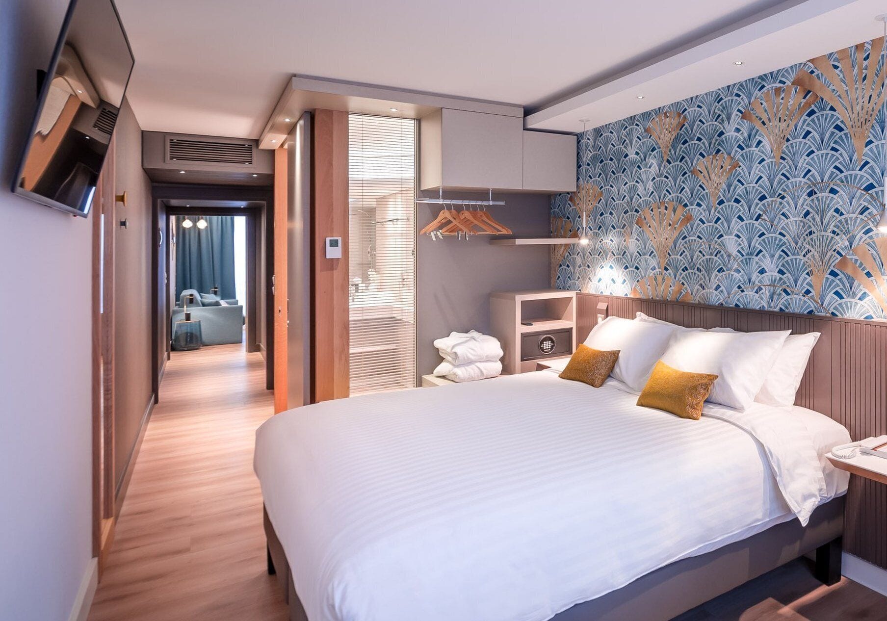Une chambre d’hôtel avec un grand lit, une table de chevet, une armoire et une salle de bain visible à travers une porte ouverte.