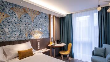 A hotel room with a bed, a desk, a chair, and a sofa.