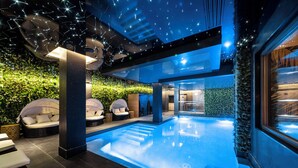 Une piscine intérieure au design moderne, entourée d’espaces aménagés pour se détendre et de verdure.