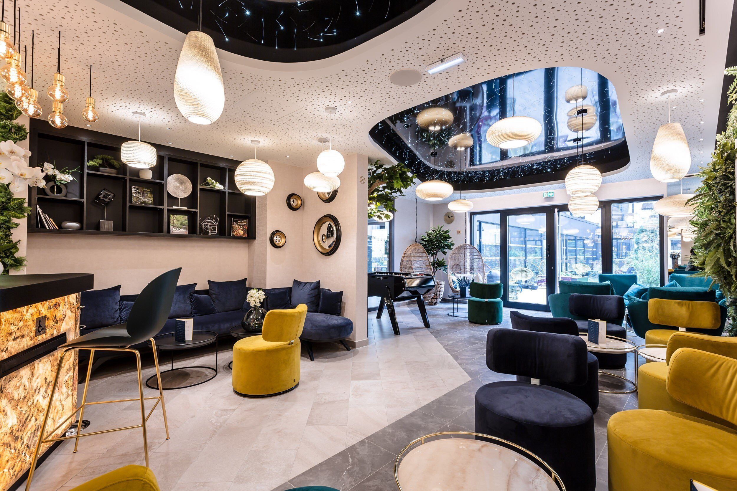 A modern lobby with a reception desk, seating areas, and a large window offering a city view.