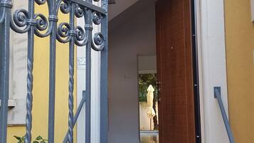 Une entrée d’immeuble avec un portail en fer forgé, une porte en bois et une petite fenêtre située au-dessus de la porte.