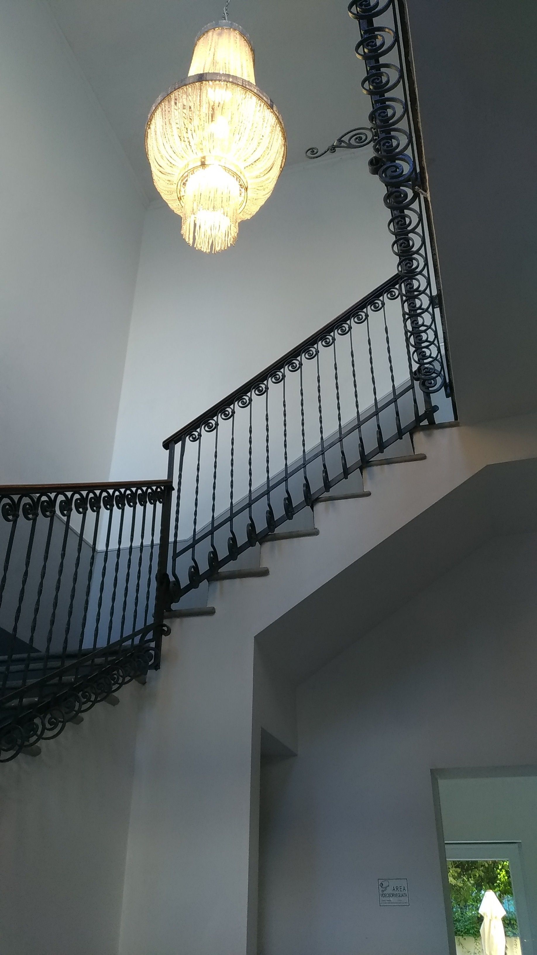 Un escalier orné de rampes noires et d’un lustre.