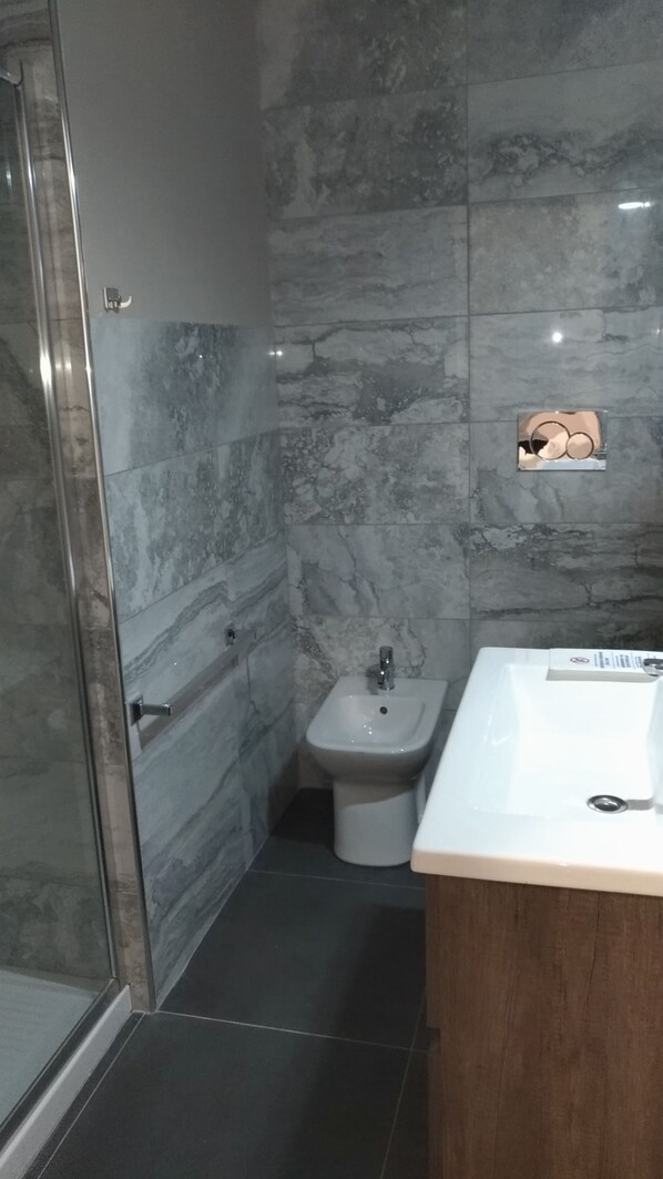 A bathroom with a shower, bidet, and sink. - Casa Liberty (Milan)