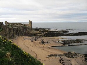 A coastal landscape with ruins and a sandy beach. - 5Pilmourplace (St. Andrews)
