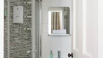 A modern bathroom with a glass-enclosed shower, a white sink, and a mirror above it.