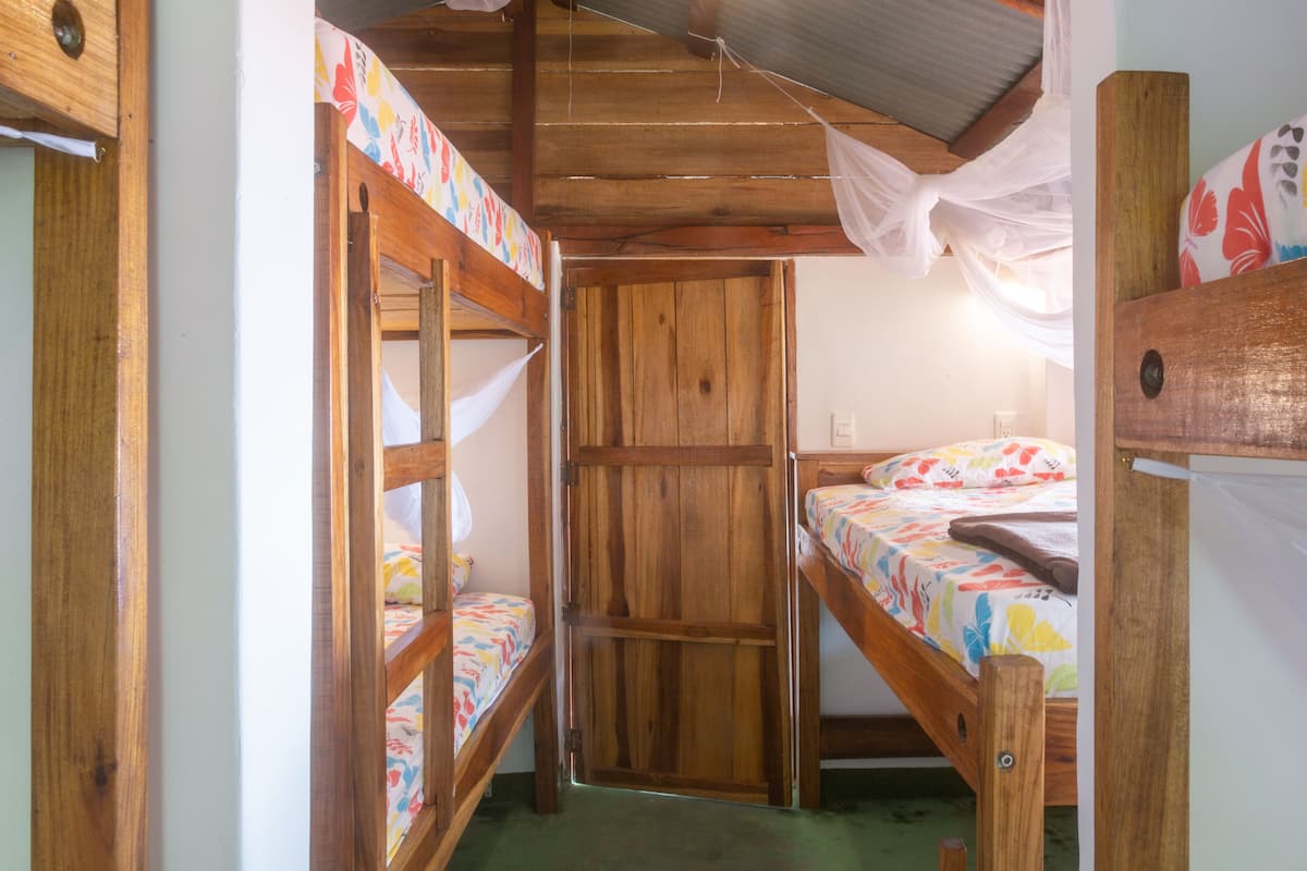 A room with bunk beds, wooden walls, and a simple, functional design.