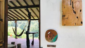 Eine Holztür führt zu einem überdachten Außenbereich mit einer Hängematte, einem Tisch und einem Schild mit der Aufschrift 'MARIPOSA'.