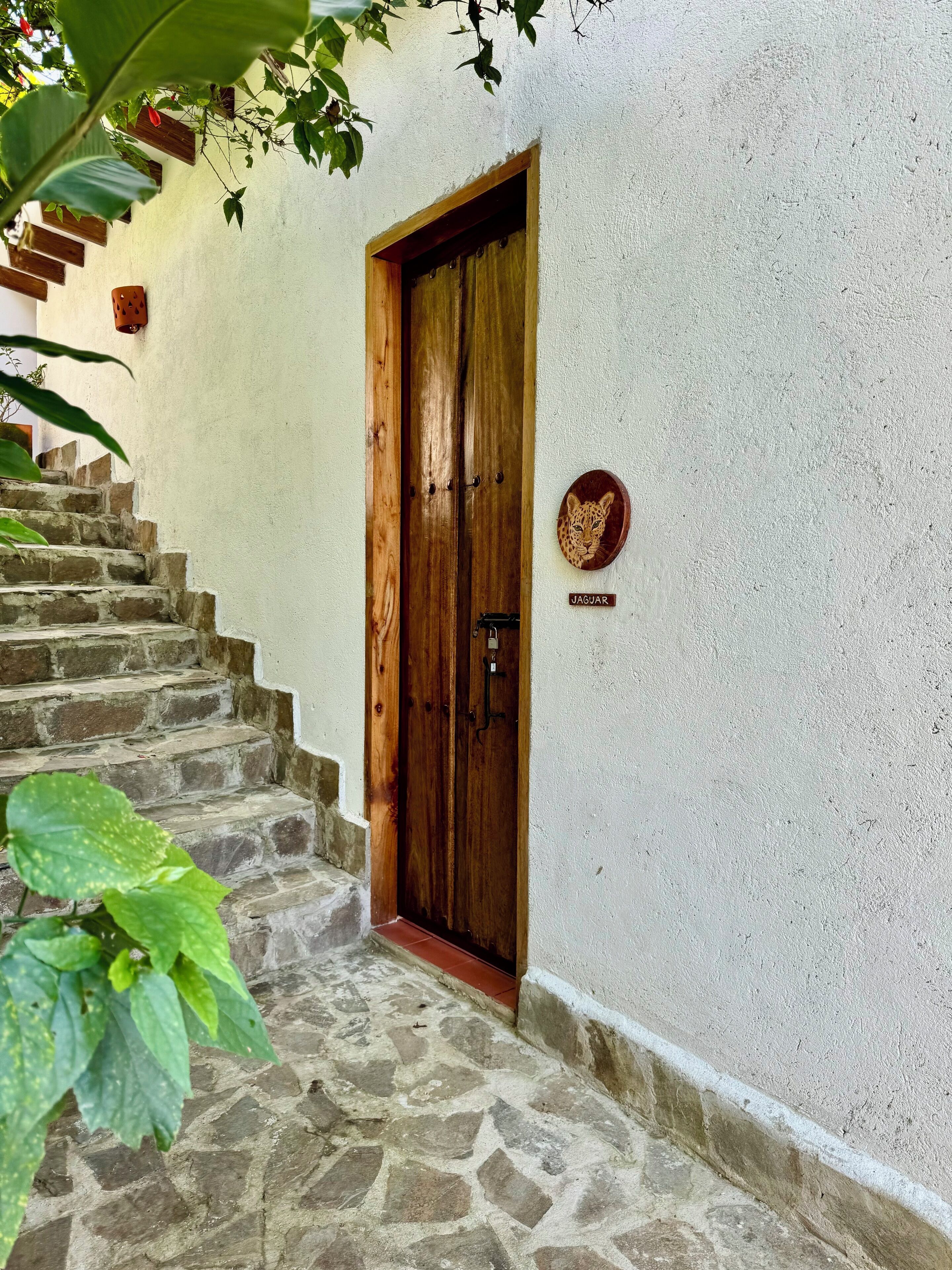Eine Holztür mit einer Jaguar-Plaque, eine Steintreppe und eine weiße Wand.