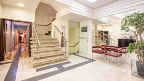 A hotel lobby with a staircase, seating area, and a potted plant. - Almasty Hotel (Chapecó)