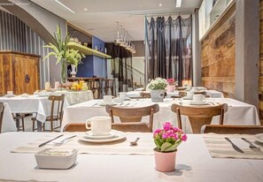A restaurant with tables set for dining, featuring a mix of wooden and upholstered chairs, and a variety of table settings including plates, cups, and cutlery. - Almasty Hotel (Chapecó)