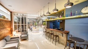 A modern bar area with a wooden counter, multiple bar stools, and a large clock on the wall. - Almasty Hotel (Chapecó)