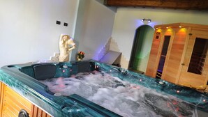 Een jacuzzi met glazen wanden, houten kasten en een standbeeld aan de muur.