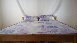 Una cama con colcha estampada con flores, dos almohadas con diseño floral y cabecera de madera.