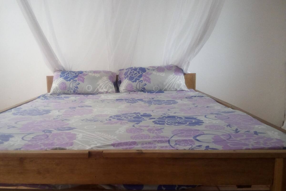A bed with a floral bedspread, two pillows with a floral pattern, and a wooden headboard.