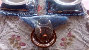 Una mesa dispuesta con platos, un vaso y un candelabro, sobre un mantel de encaje.