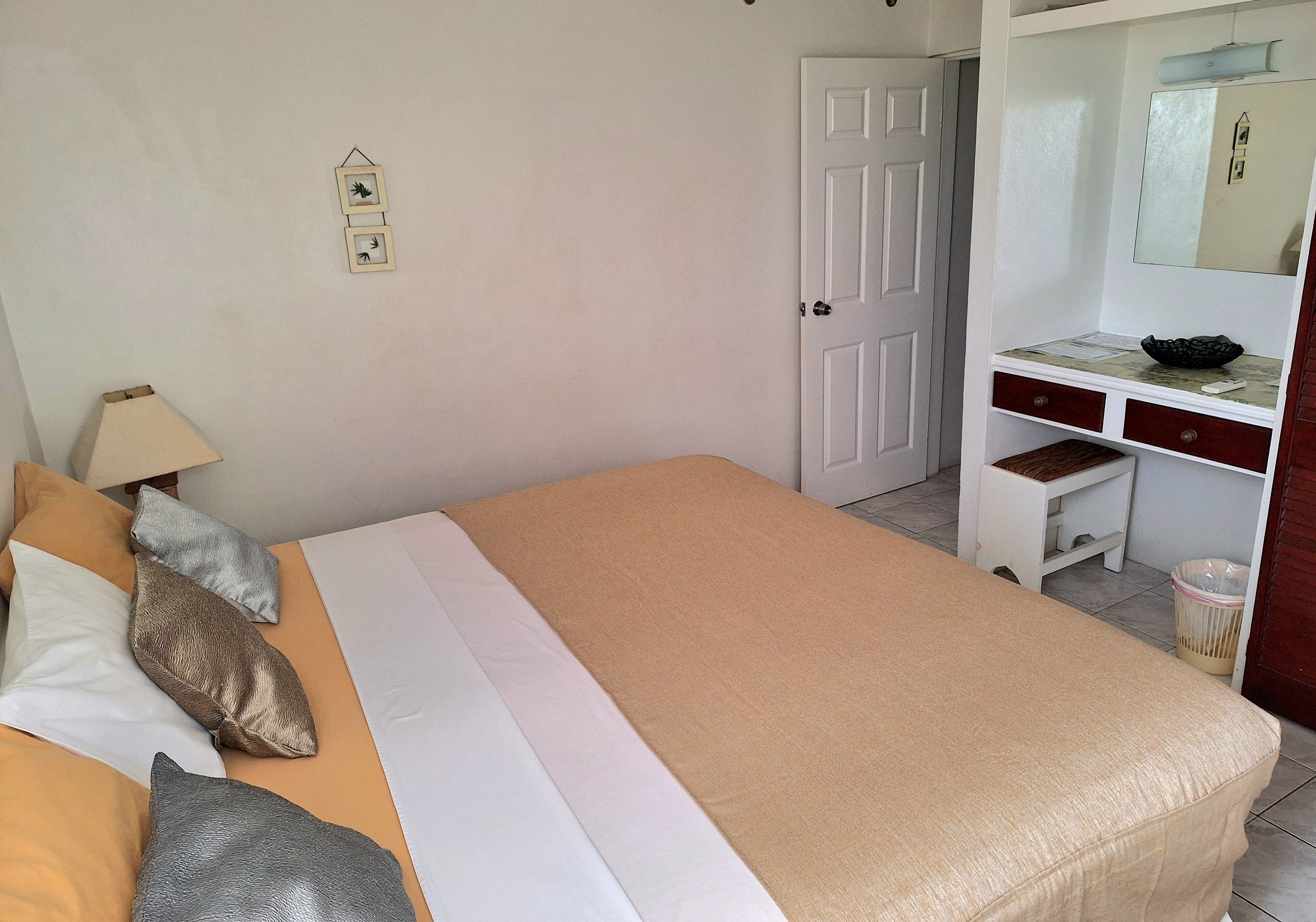 Un dormitorio con cama, escritorio, silla y espejo.