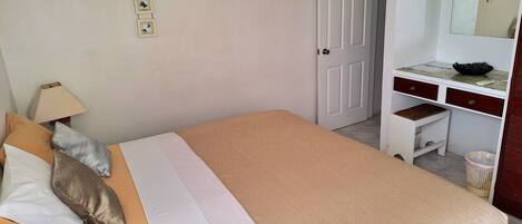 Un dormitorio con cama, escritorio, silla y espejo.