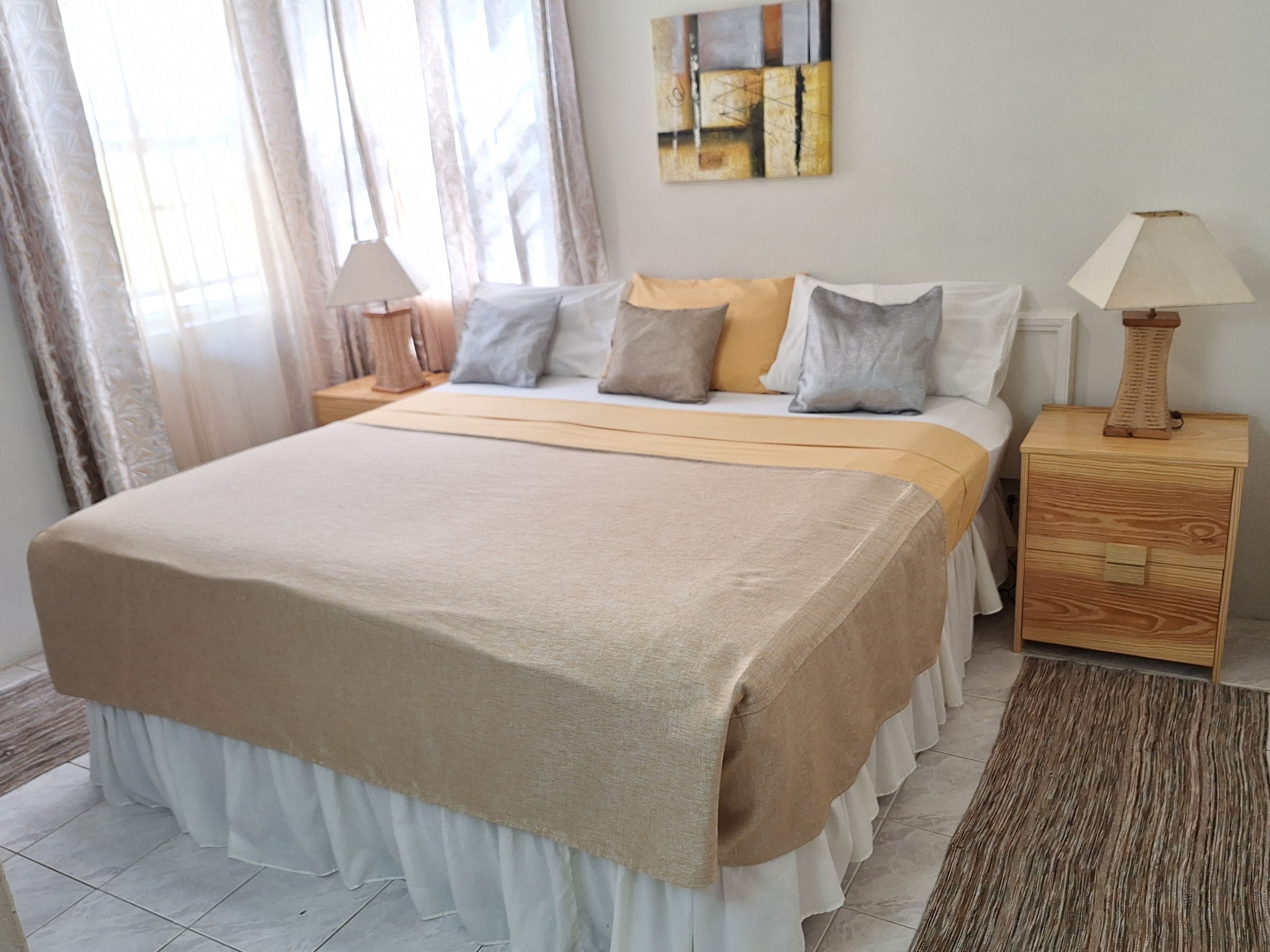 A bedroom with a bed, bedside tables, a lamp, and a painting on the wall.