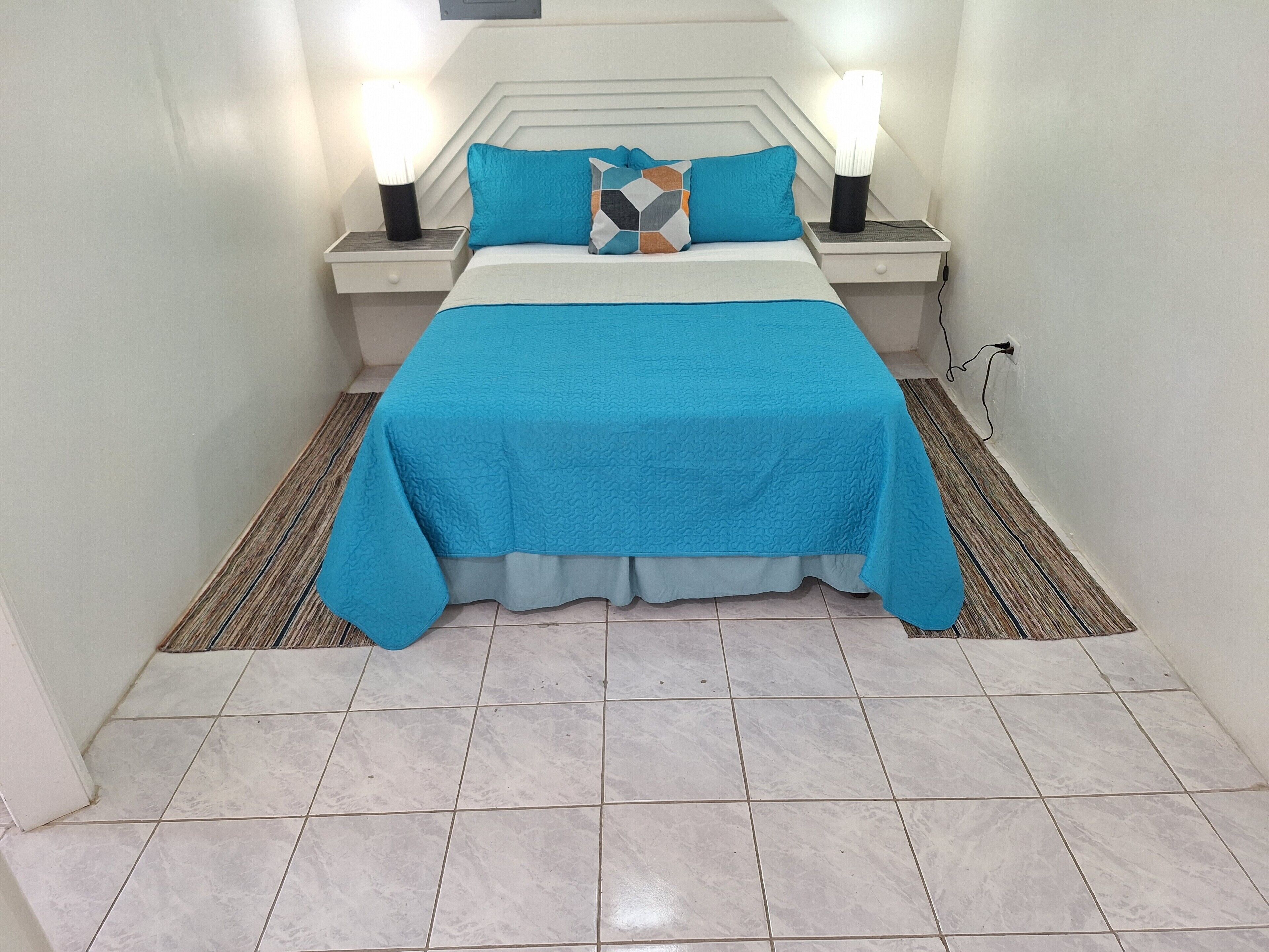 Quarto bem arrumado com cama, duas mesas de cabeceira e um criado-mudo.