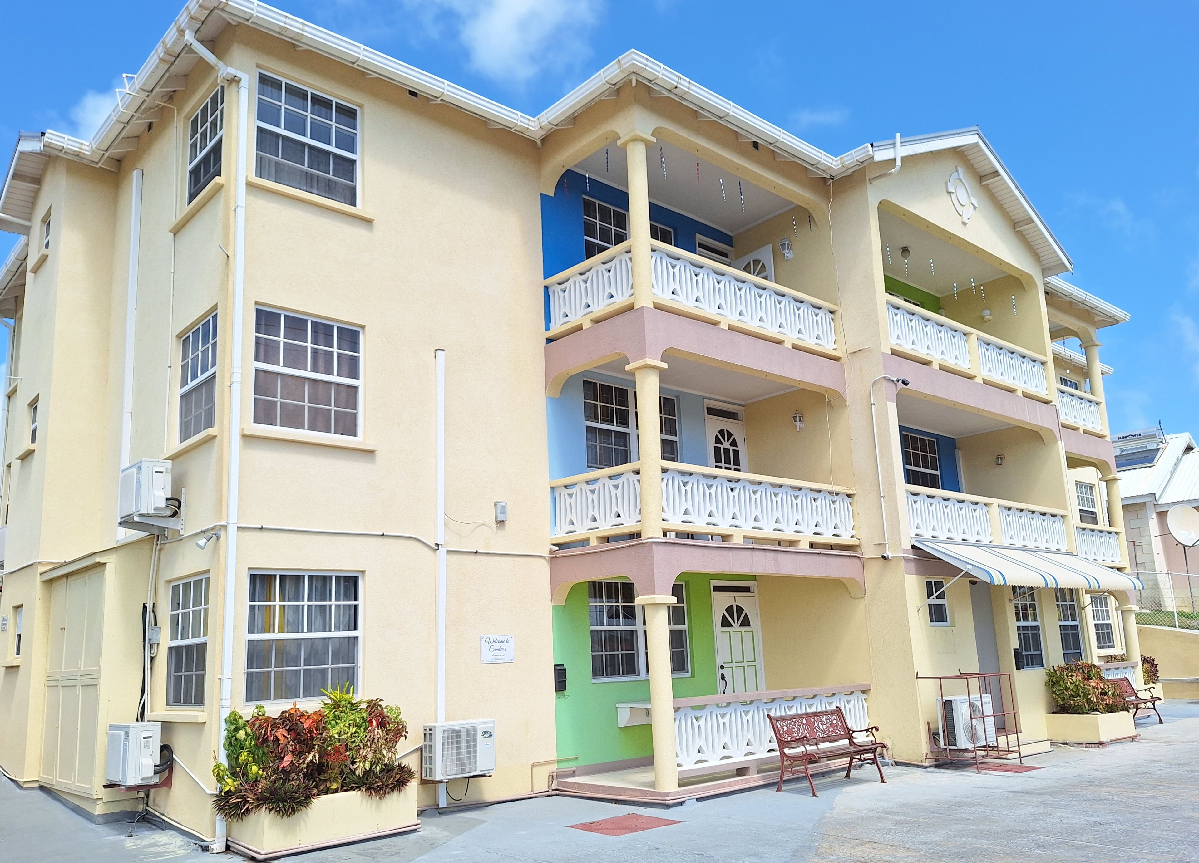 A multi-story building with balconies, air conditioning units, and a sign welcoming visitors.