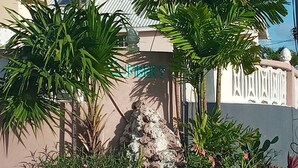 A landscaped area with palm trees and flowering plants. - Cumber's Tropical Apartments (Oistins)