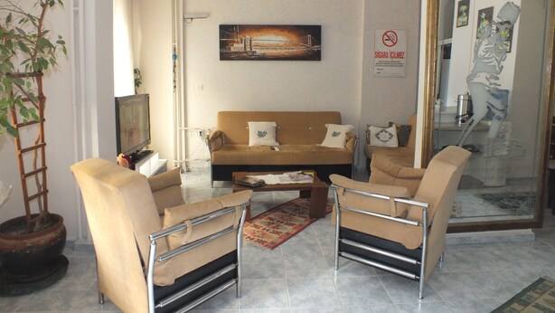 A living room with a sofa, two armchairs, a coffee table, and a television. - Arden Pansiyon (Çanakkale)