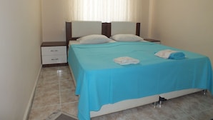A neatly made bed with a blue bedspread, two pillows, and a folded towel on the side. - Arden Pansiyon (Çanakkale)