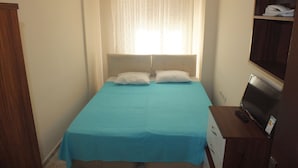 A bedroom with a bed, a wooden wardrobe, a desk with a computer, and a window with curtains. - Arden Pansiyon (Çanakkale)
