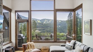 Ein gemütliches Wohnzimmer mit einem großen Fenster und Blick auf eine malerische Berglandschaft.