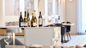 A dining area with a wine selection on a counter, a table with cutlery, and a modern interior design. - Hotel Gasthof Zum Bad (Langenau)