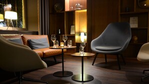 A modern lounge area with a sofa, two chairs, a small round table with glasses, and a lamp. - Hotel Gasthof Zum Bad (Langenau)